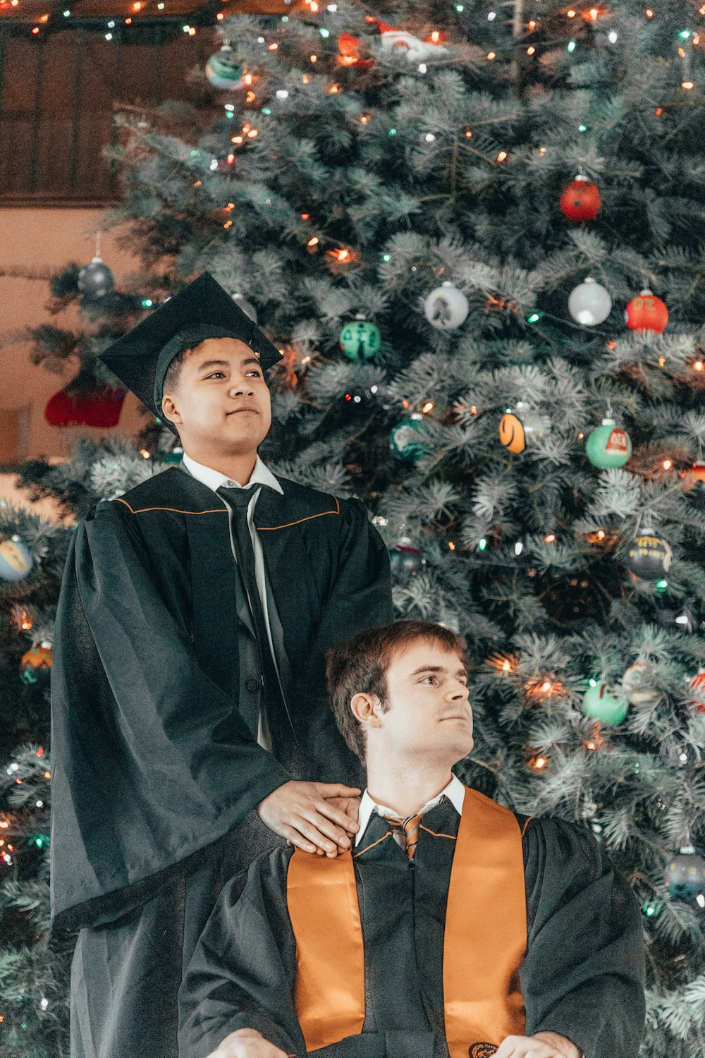 a man sitting in a wheel chair next to a man in a graduation gown