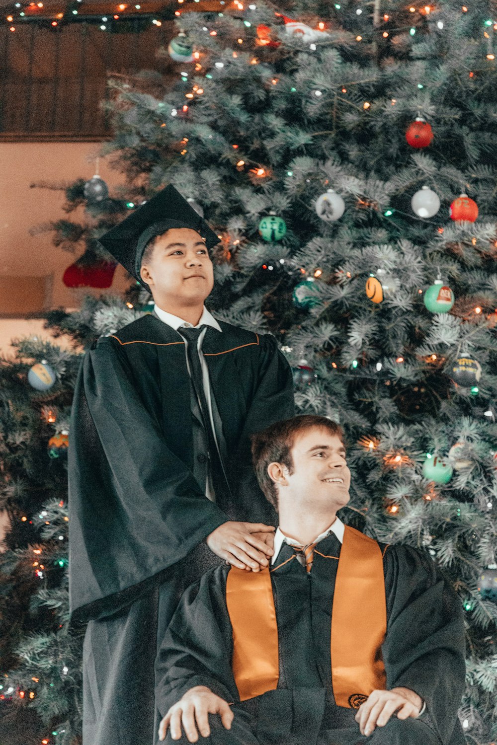 a man sitting in a wheel chair in front of a christmas tree