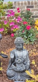 A peaceful garden with blooming flowers and a small Buddha statue.