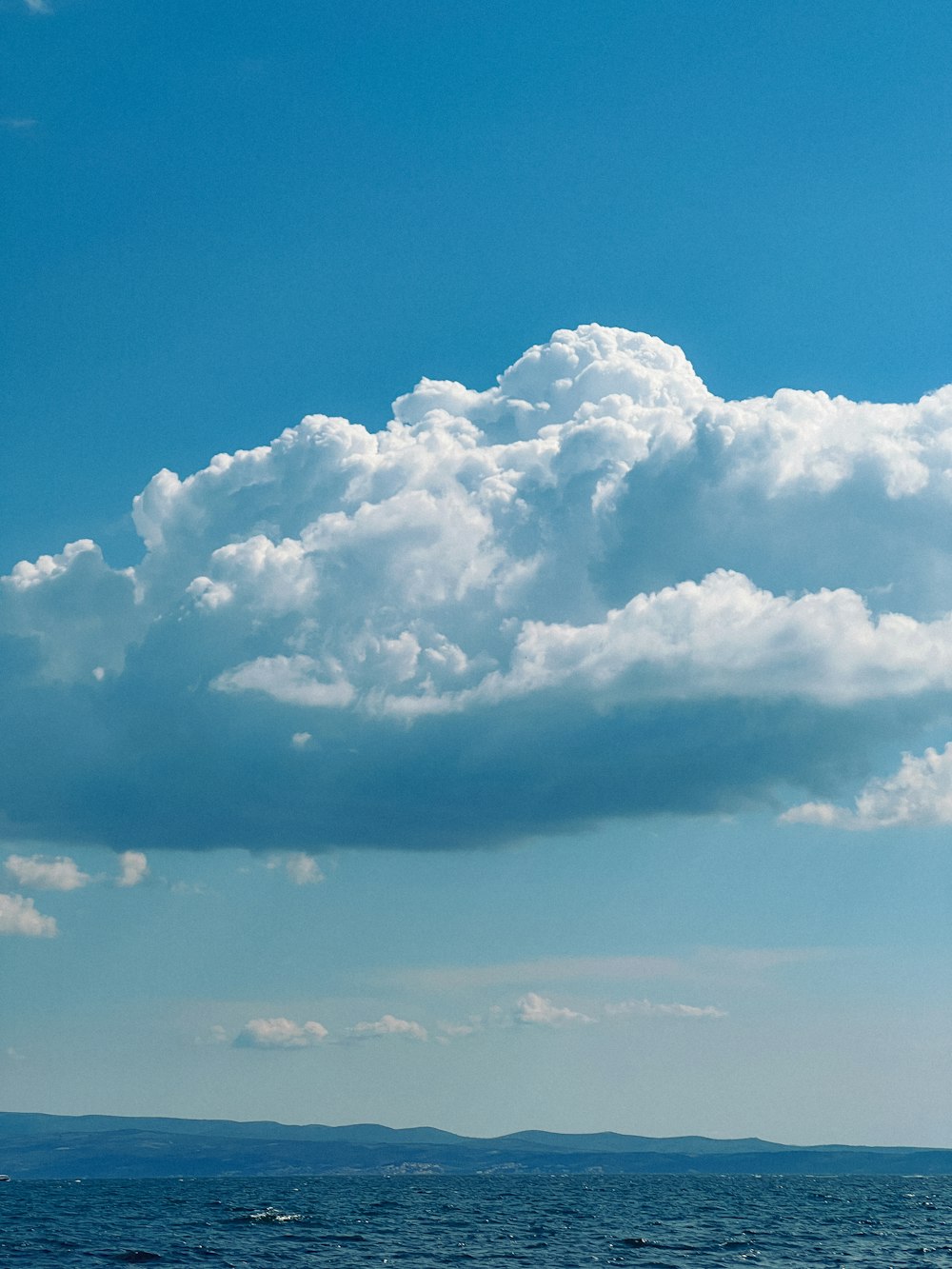 a boat floating on top of a body of water under a cloudy blue sky