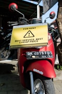 a red scooter parked next to a tree