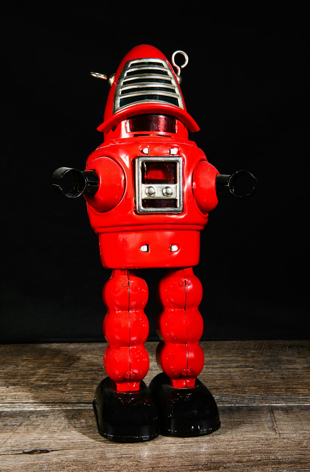 a red toy robot standing on top of a wooden floor