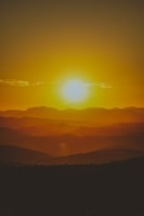 Bright watercolor landscape capturing the warmth of a sunset over hills.