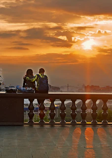 A caregiver and client sitting side by side on a porch swing, sharing a peaceful moment watching the sunset.