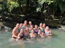 A group of women smiling together outdoors during a hiking trip in a lush green forest.