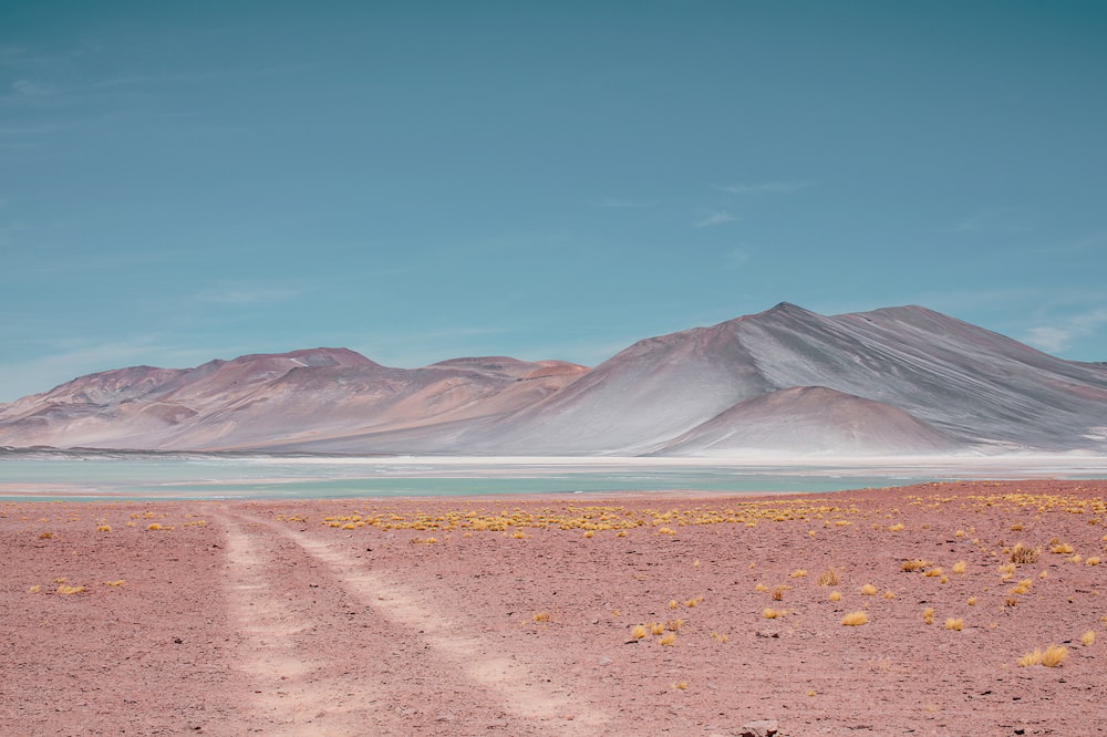 a dirt road in the desert with mountains in the background