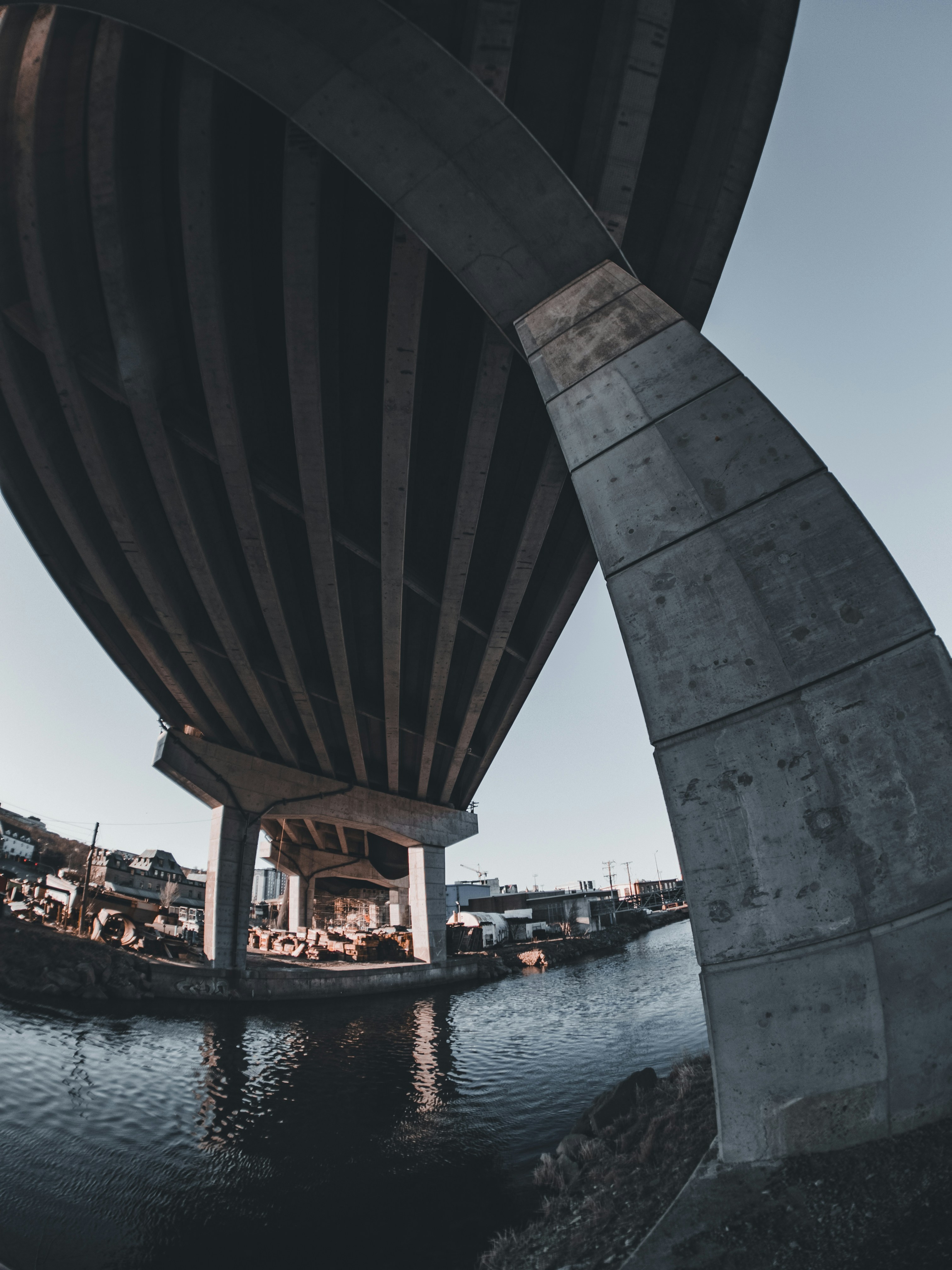 Bridge construction over river, concrete pillars and steel beams, dim twilight industrial setting