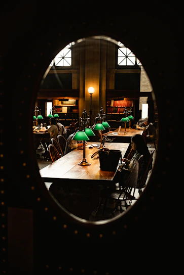 A cozy workspace with writers collaborating over manuscripts and laptops, surrounded by books and warm lighting.