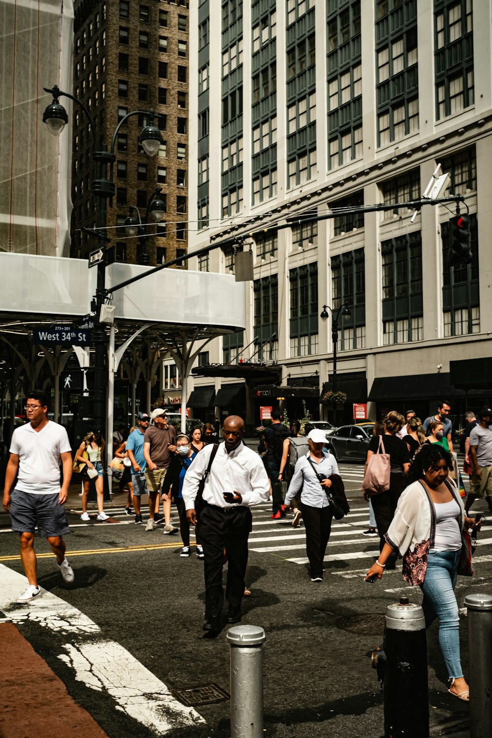 a group of people walking across a street next to tall buildings