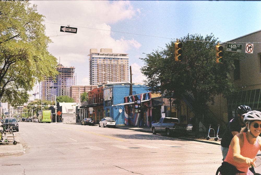 a woman riding a bike down a street next to tall buildings