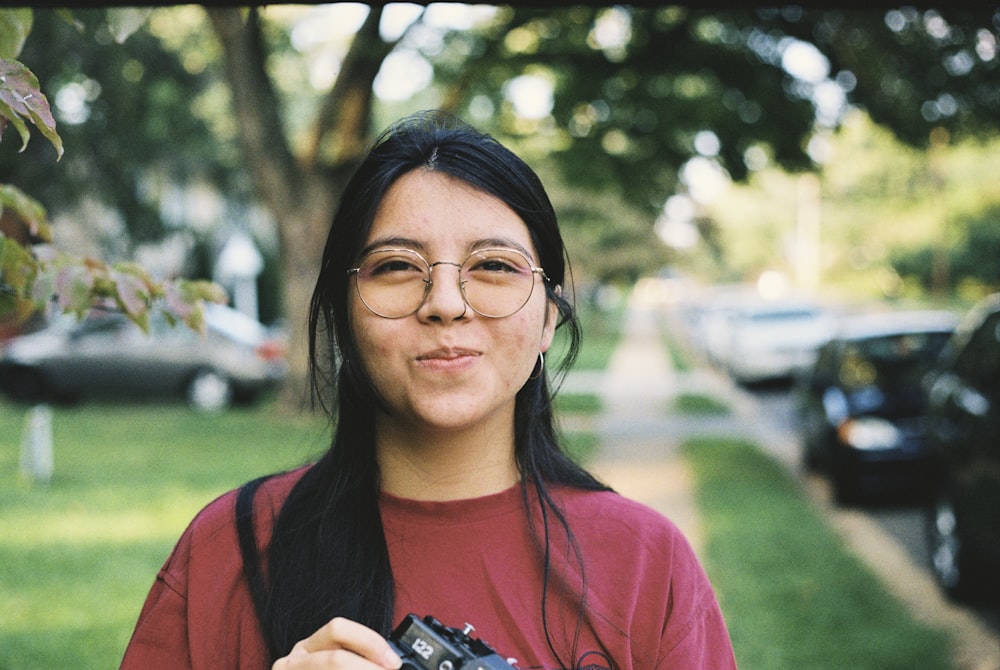 a woman holding a camera in front of a tree