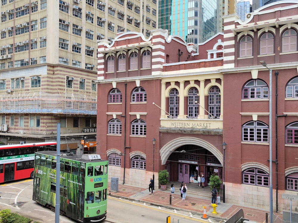 a green double decker bus parked in front of a building