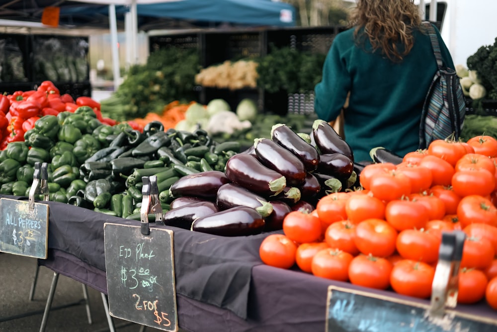 a woman standing in front of a table full of vegetables