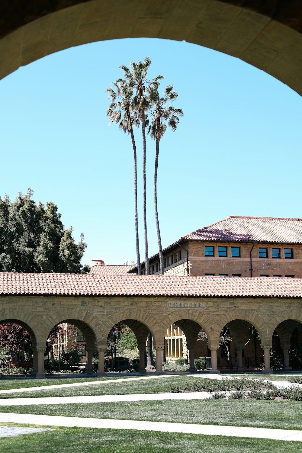 a building with arches and palm trees in the background