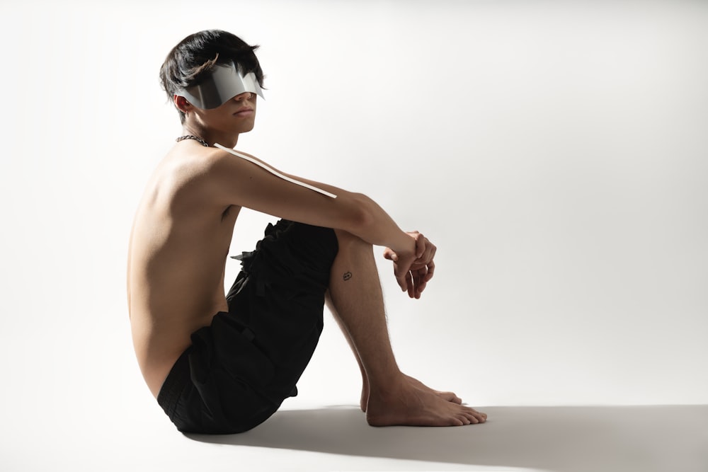 a man with a blindfold sitting on the ground