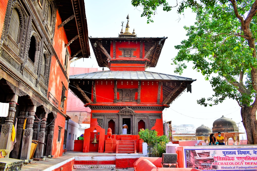 a red building with a tall tower next to a tree