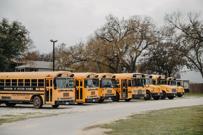 A row of yellow school buses parked side by side, a reminder that transportation affects daily school attendance