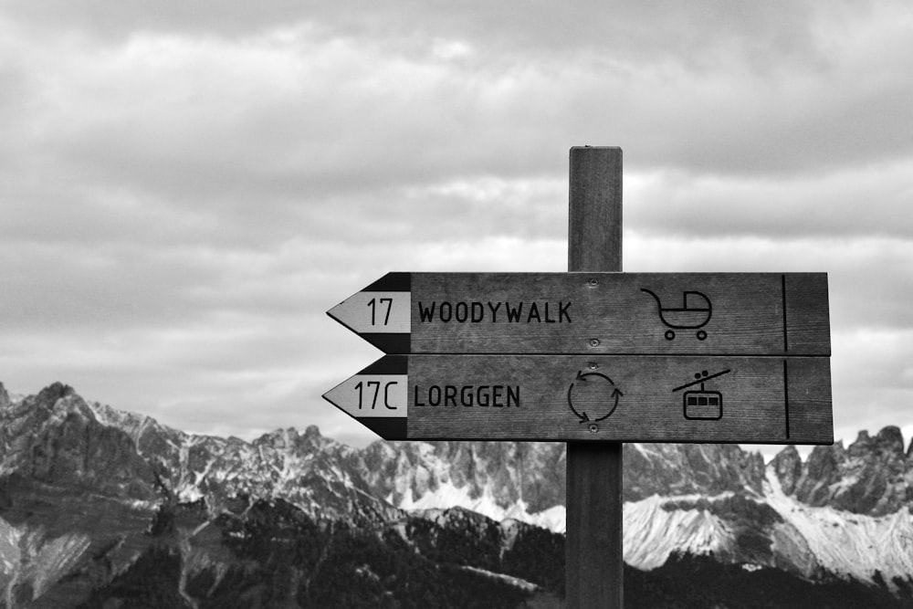 Una foto en blanco y negro de un letrero con montañas en el fondo