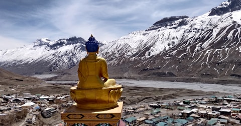 a golden buddha statue sitting on top of a mountain
