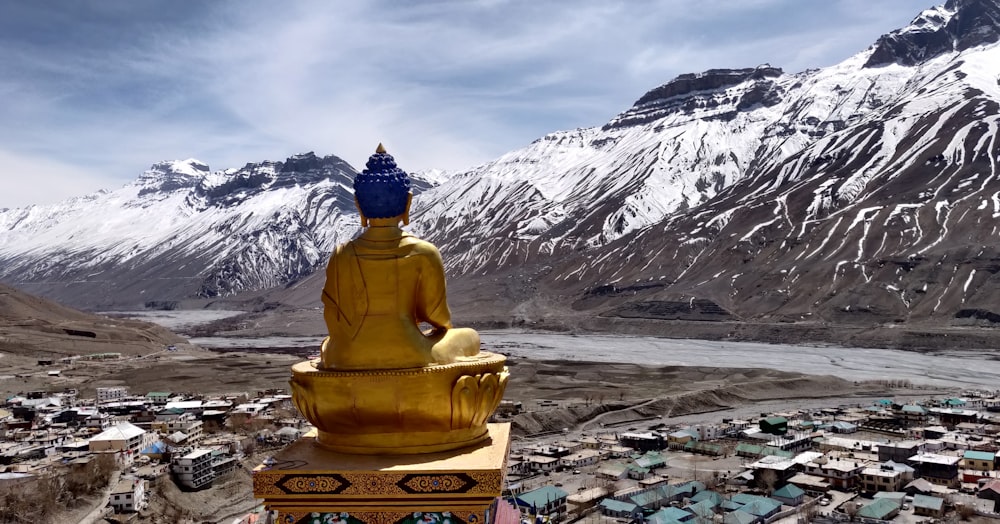 a golden buddha statue sitting on top of a mountain