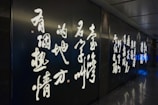 A series of illuminated traditional Chinese calligraphy characters on a dark wall in a dimly lit hallway.