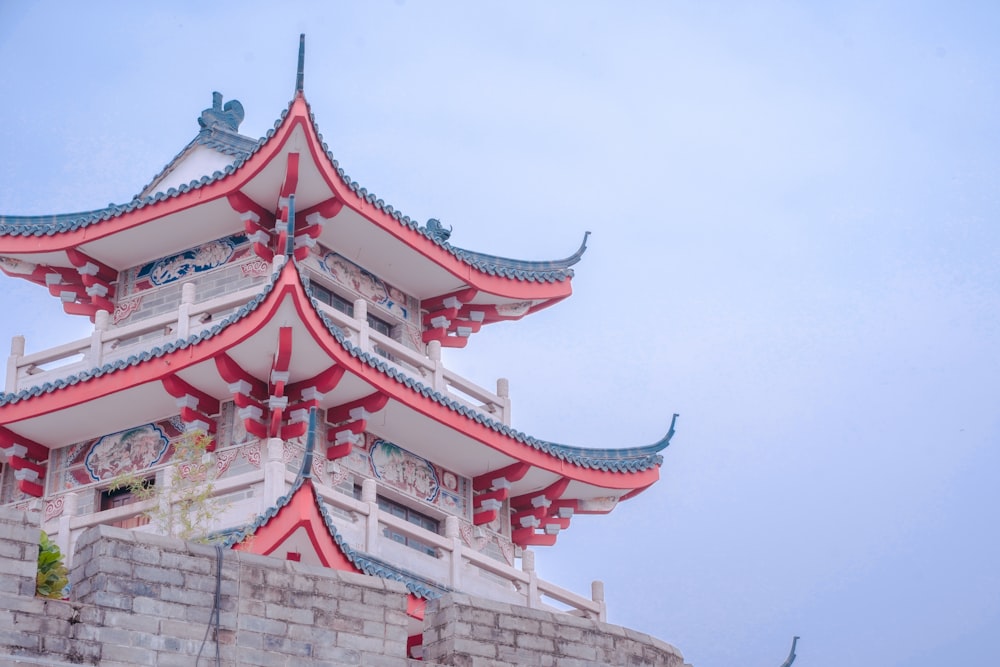 a tall red and white building sitting on top of a stone wall