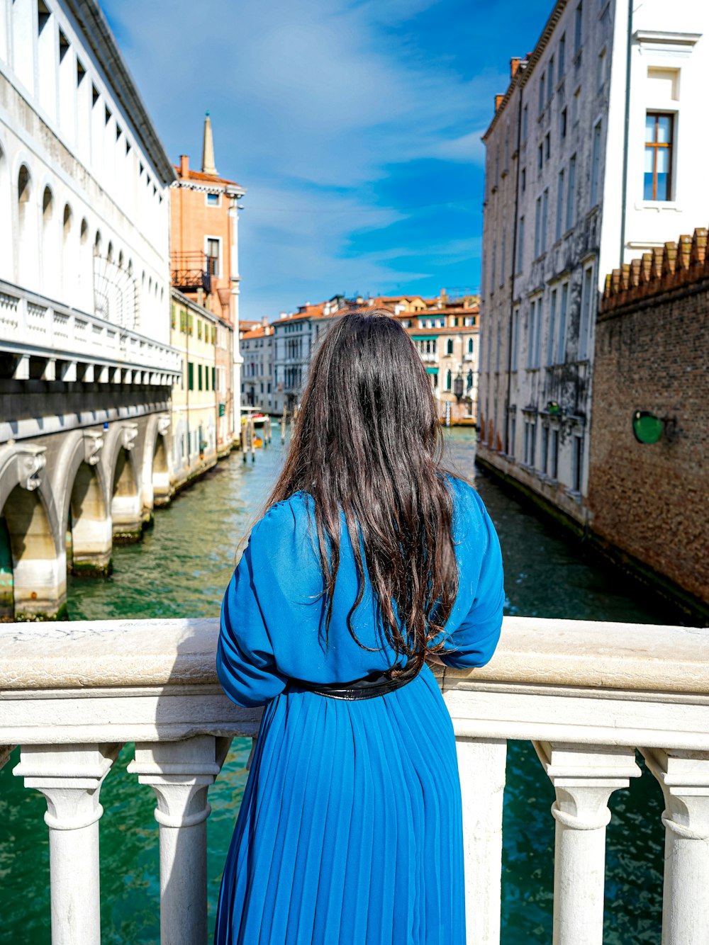 a woman in a blue dress standing on a bridge