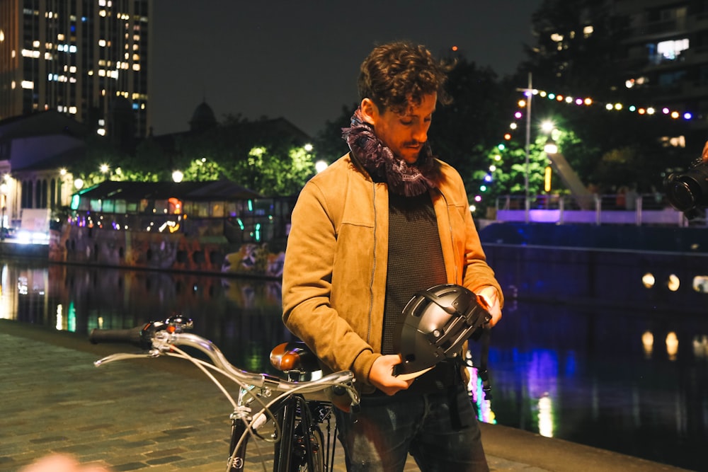 a man standing next to a bike holding a helmet