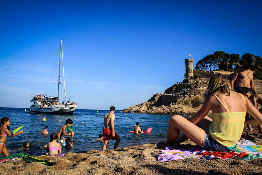 a group of people sitting on top of a sandy beach