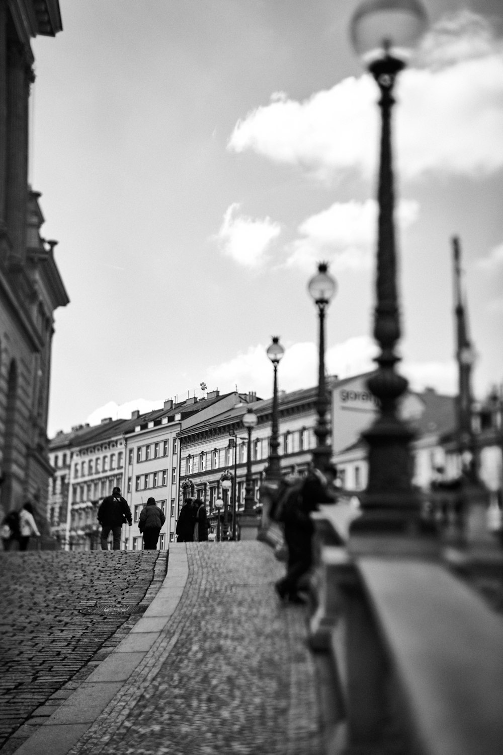 a black and white photo of people walking on a cobblestone street