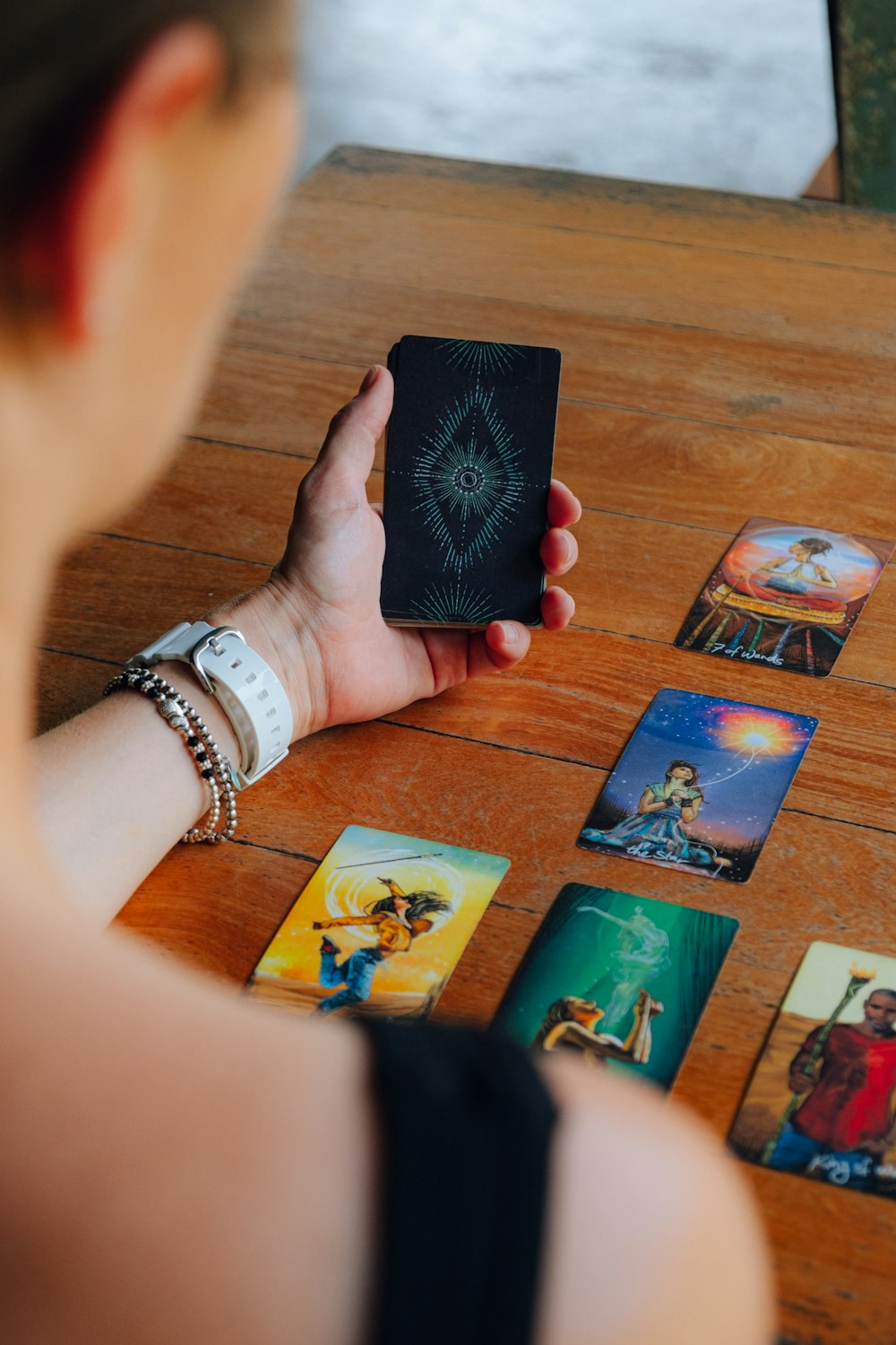 a woman holding up a card on top of a wooden table