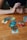 A wooden table with several tarot cards laid out, depicting various images and symbols. A person's hands are visible, holding a deck of cards ready for reading. The atmosphere suggests a moment of concentration and mystery.