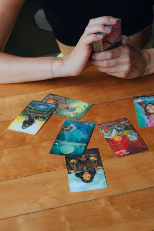 A close-up of hands gently shuffling tarot cards over a smooth wooden table.