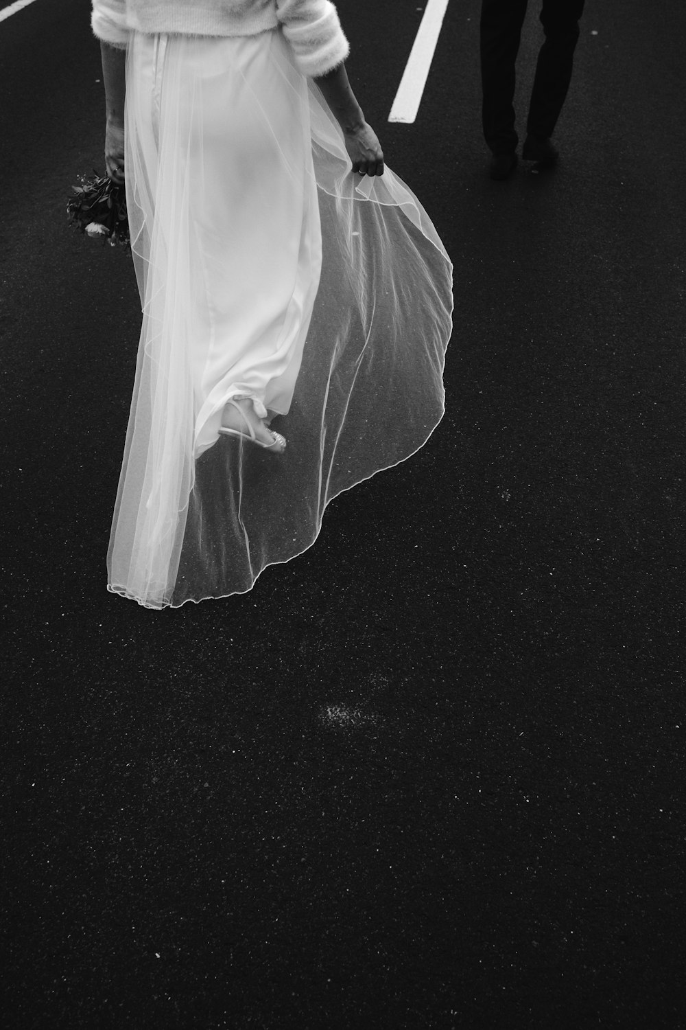a woman in a white dress is walking down the street