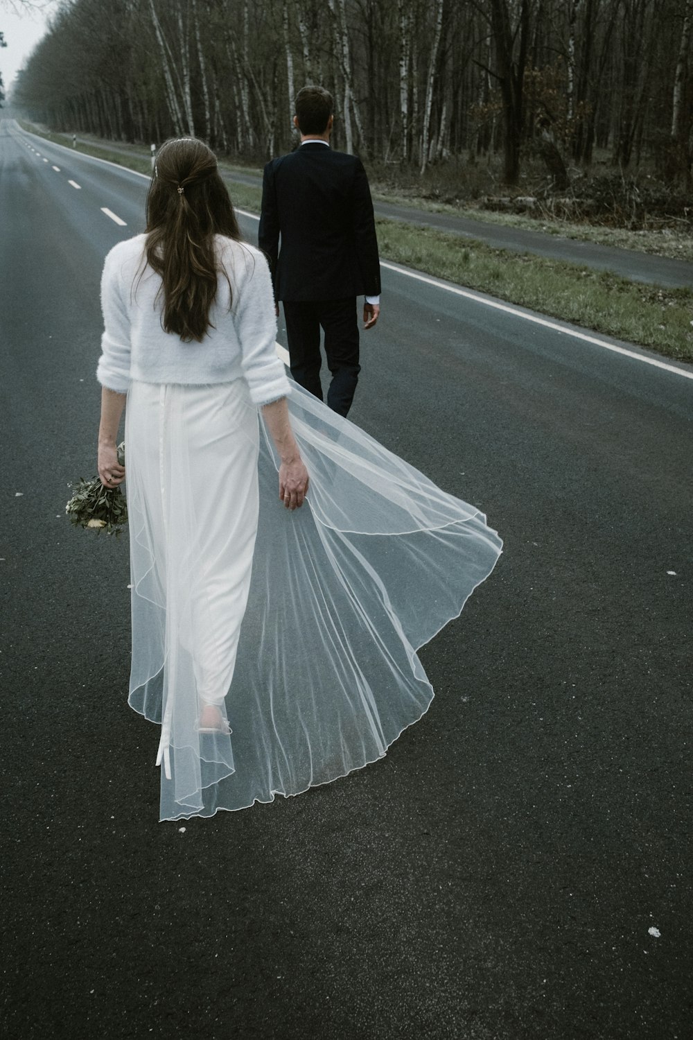 a bride and groom walking down the road