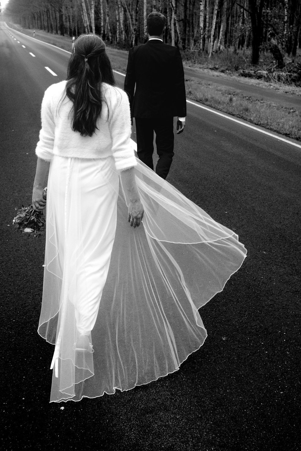 a man and woman walking down a road holding hands