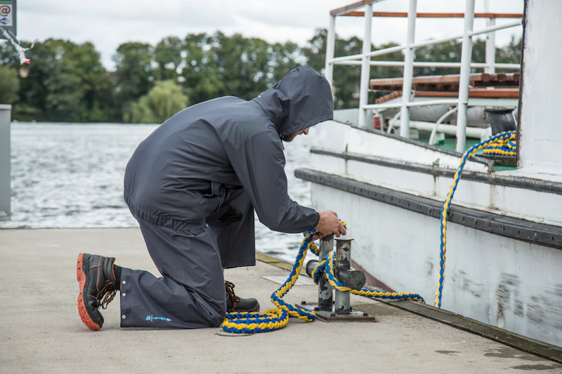 Worker in waterproof raincoat on a boat in heavy rain