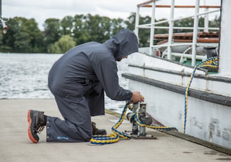 a man in a raincoat is working on a boat