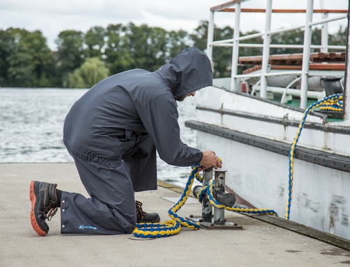 a man in a raincoat is working on a boat