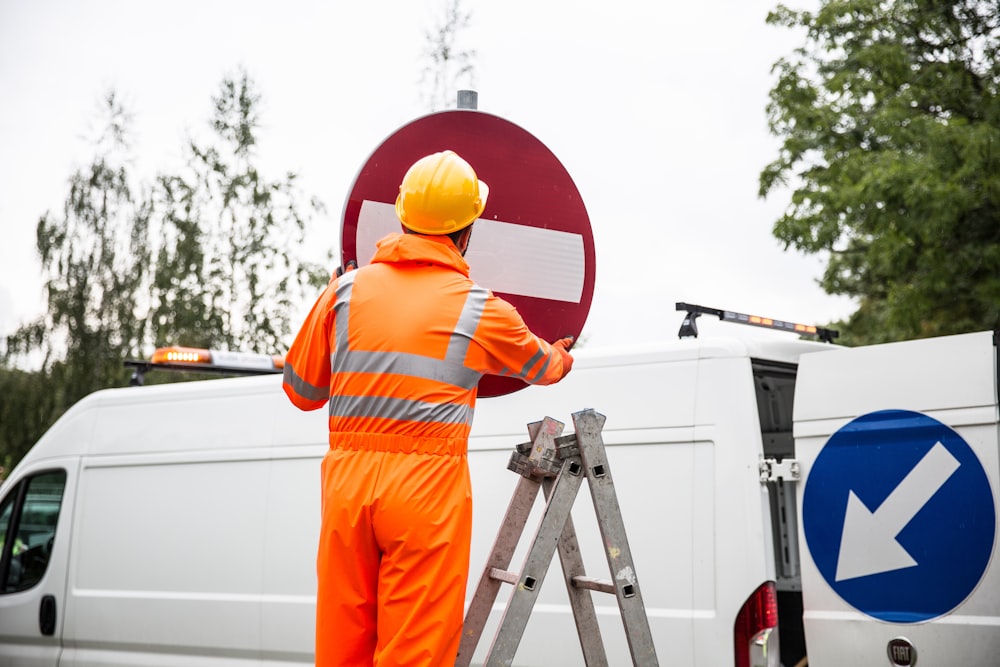 a man in an orange safety suit painting a sign