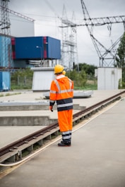 a man in an orange safety suit standing on a train track