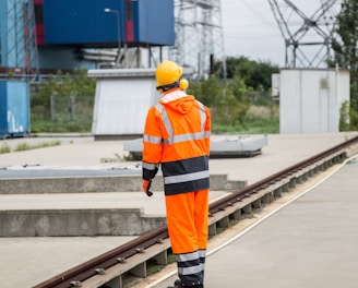 a man in an orange safety suit standing on a train track