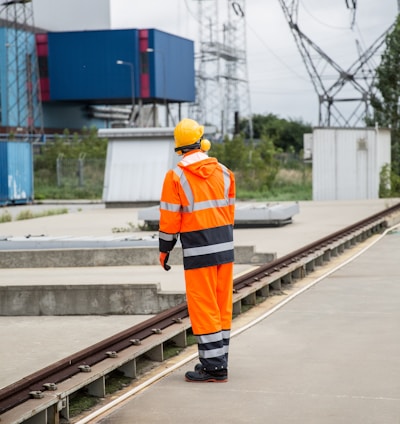 a man in an orange safety suit standing on a train track