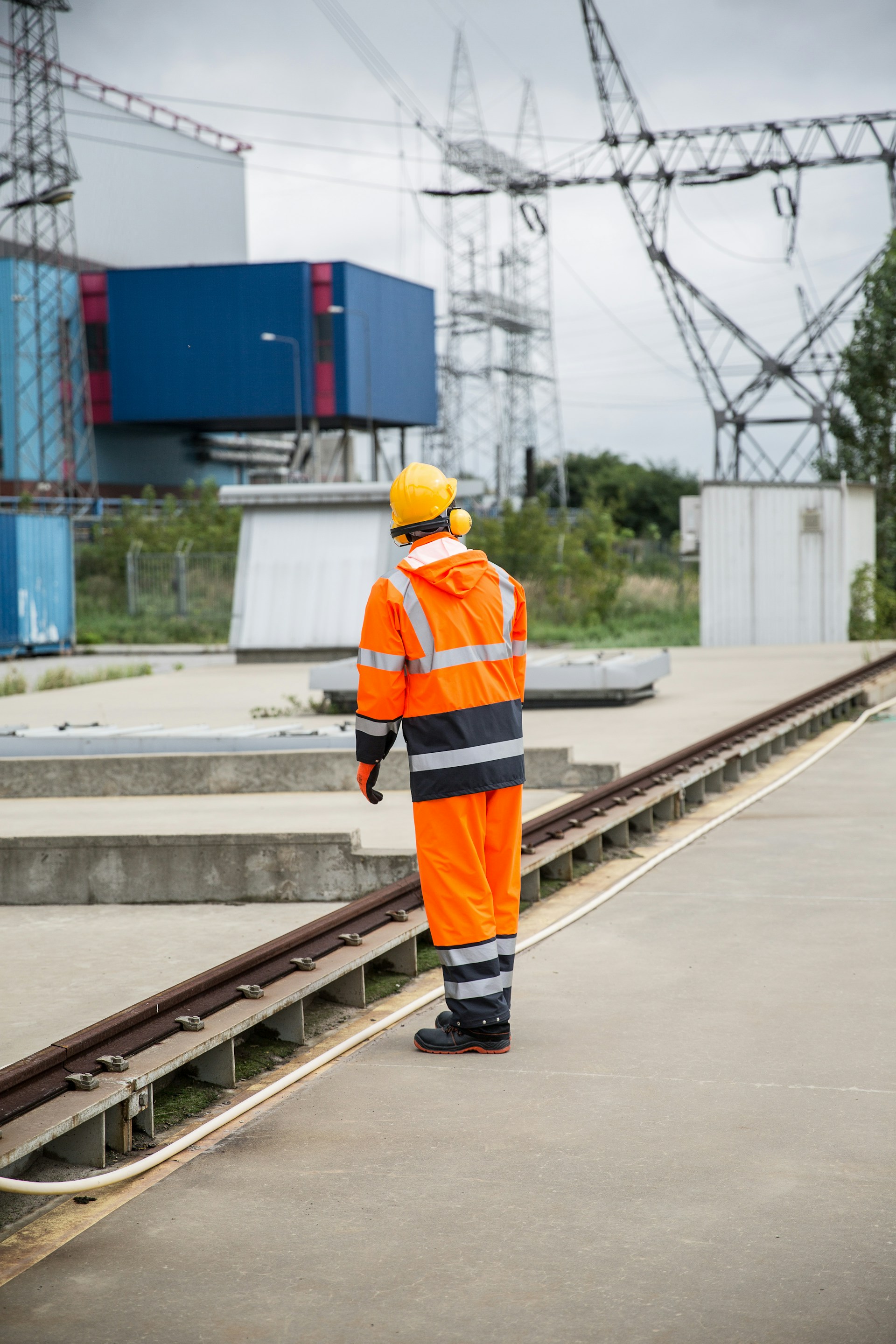 a man in an orange safety suit standing on a train track