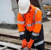 a man in an orange safety jacket working on a metal rail