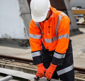 a man in an orange safety jacket working on a metal rail