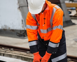 a man in an orange safety jacket working on a metal rail