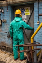 a man in a green coverall standing in front of a blue building