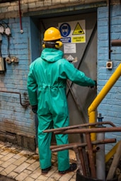 a man in a green coverall standing in front of a blue building