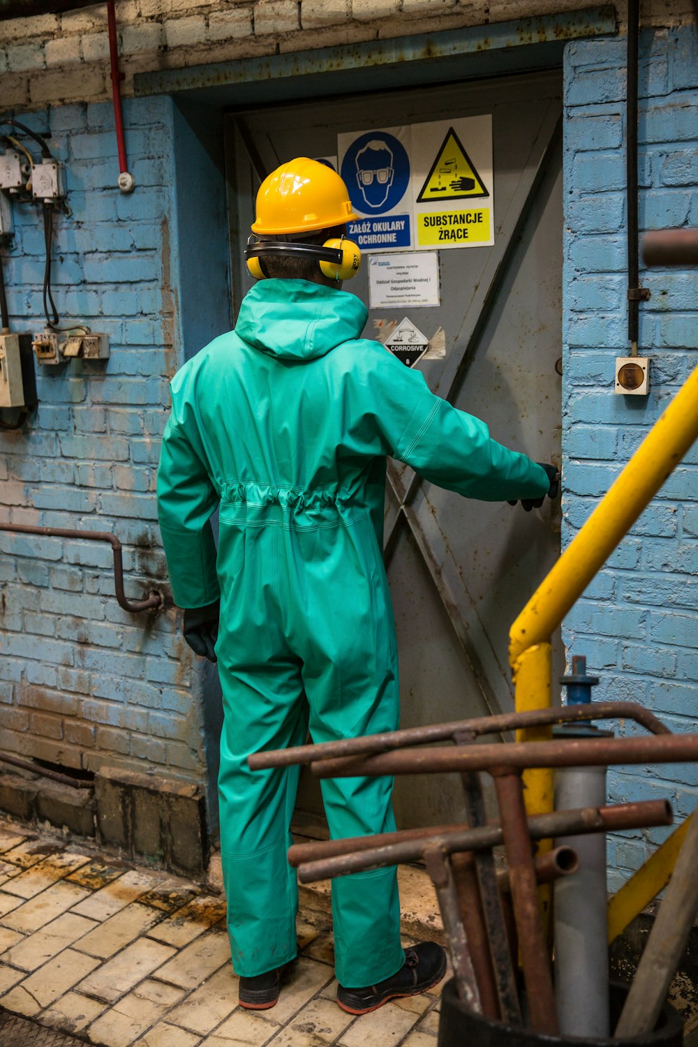 a man in a green coverall standing in front of a blue building